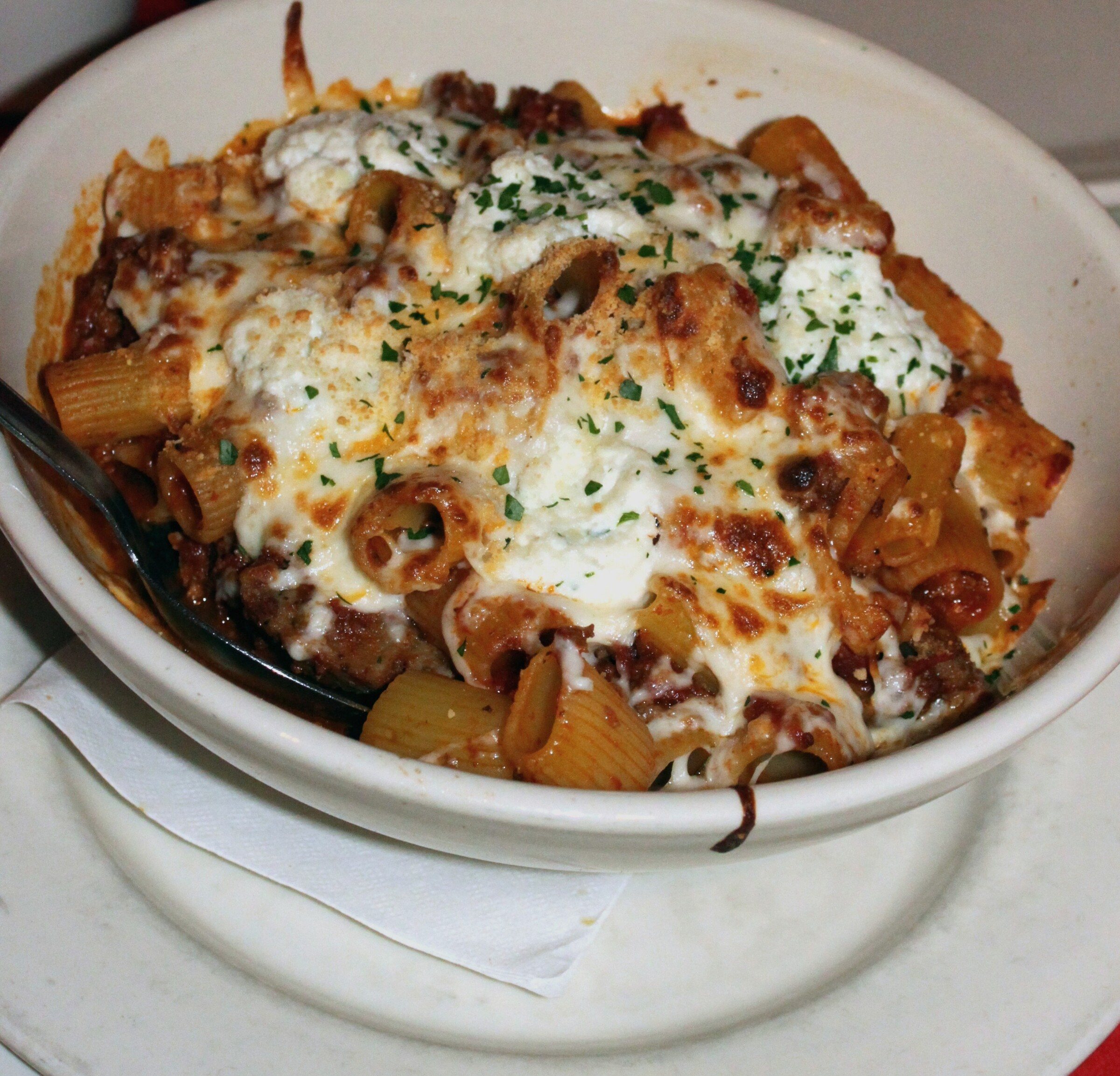 Baked ziti with melted mozzarella and ricotta in a white dish