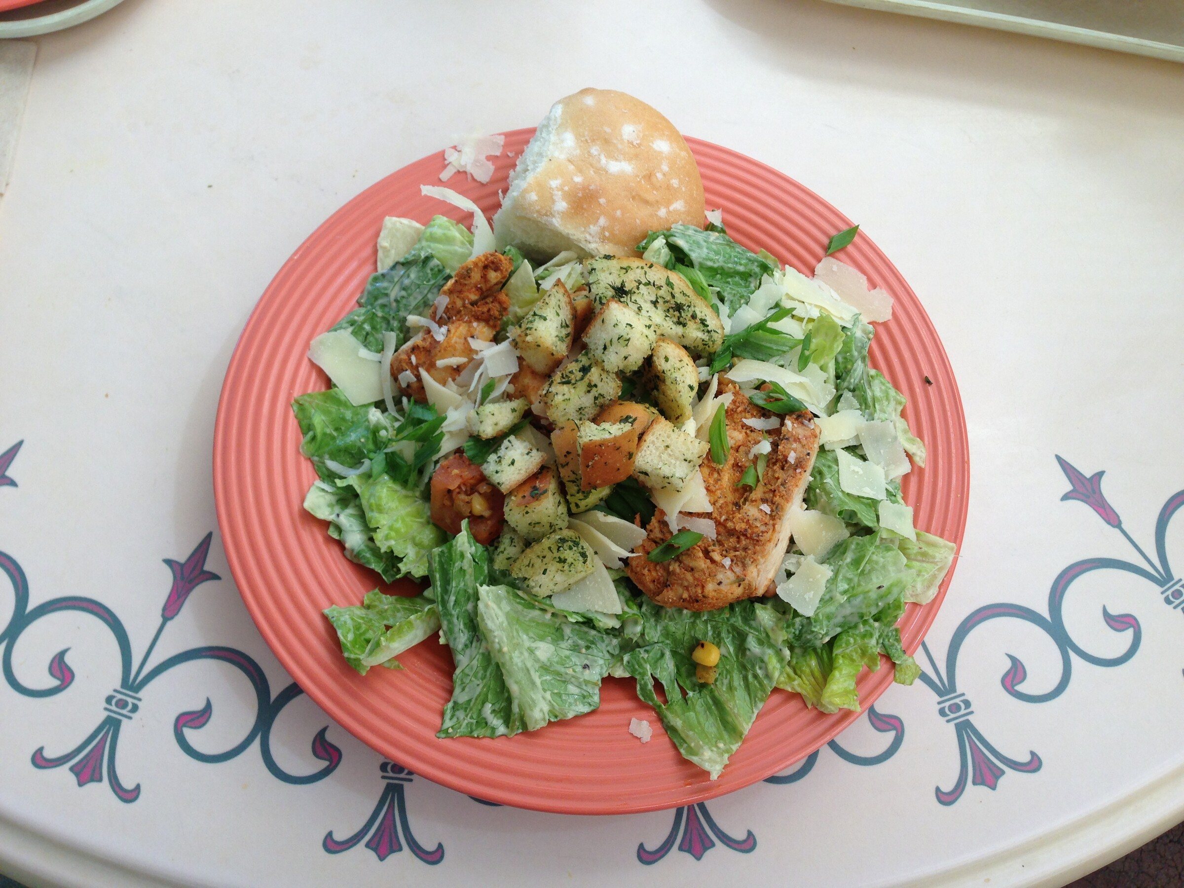 A chicken Caesar salad with romaine lettuce and Parmesan on a plate