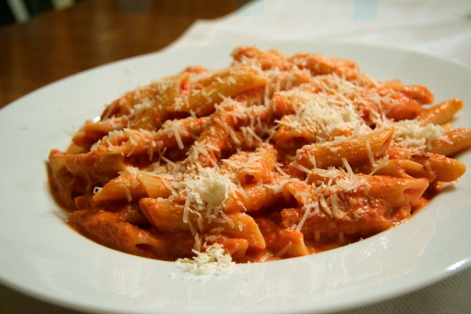 Penne alla vodka in a creamy pink sauce topped with Parmesan