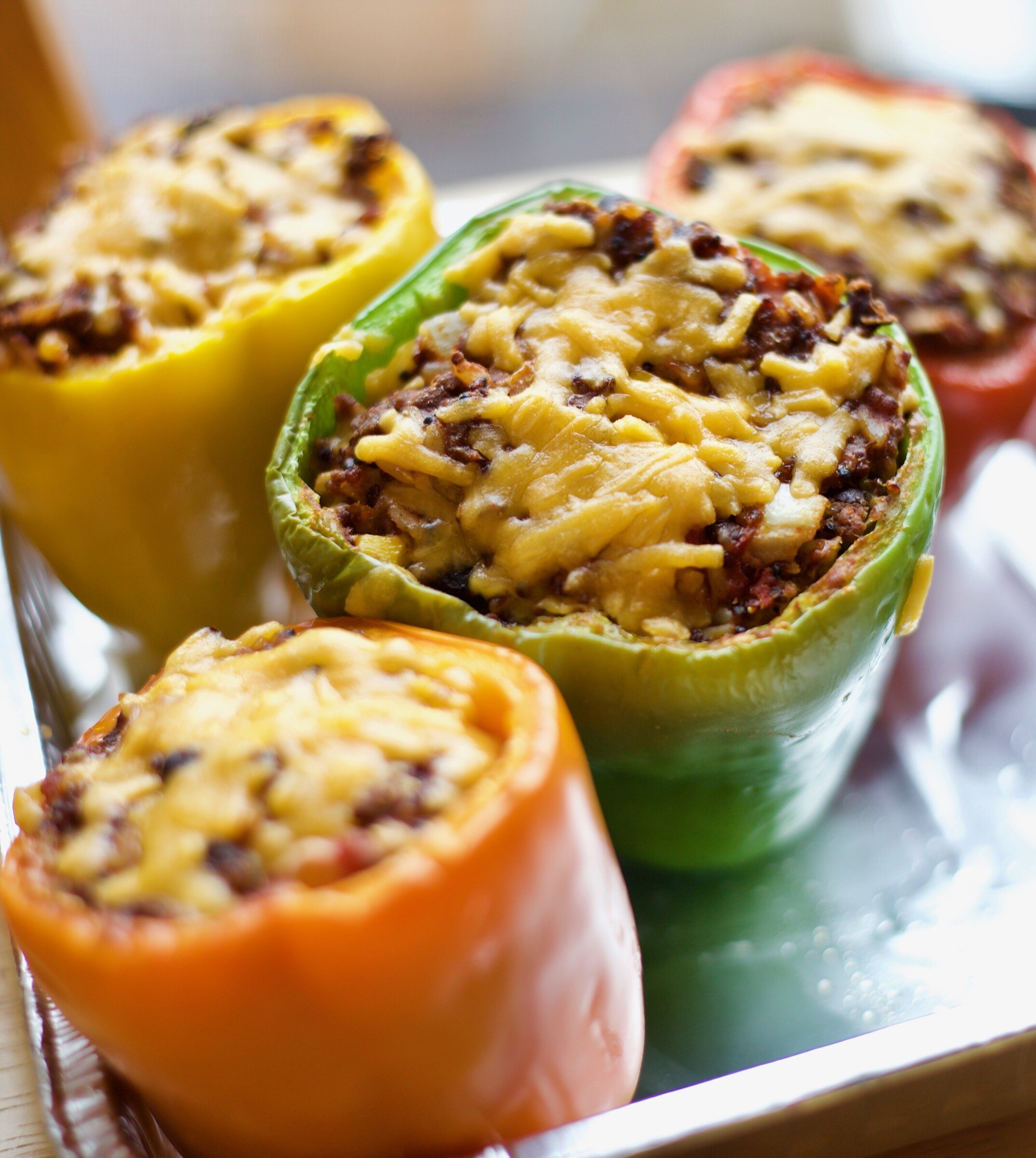 Yellow, green and orange stuffed bell peppers topped with melted cheese
