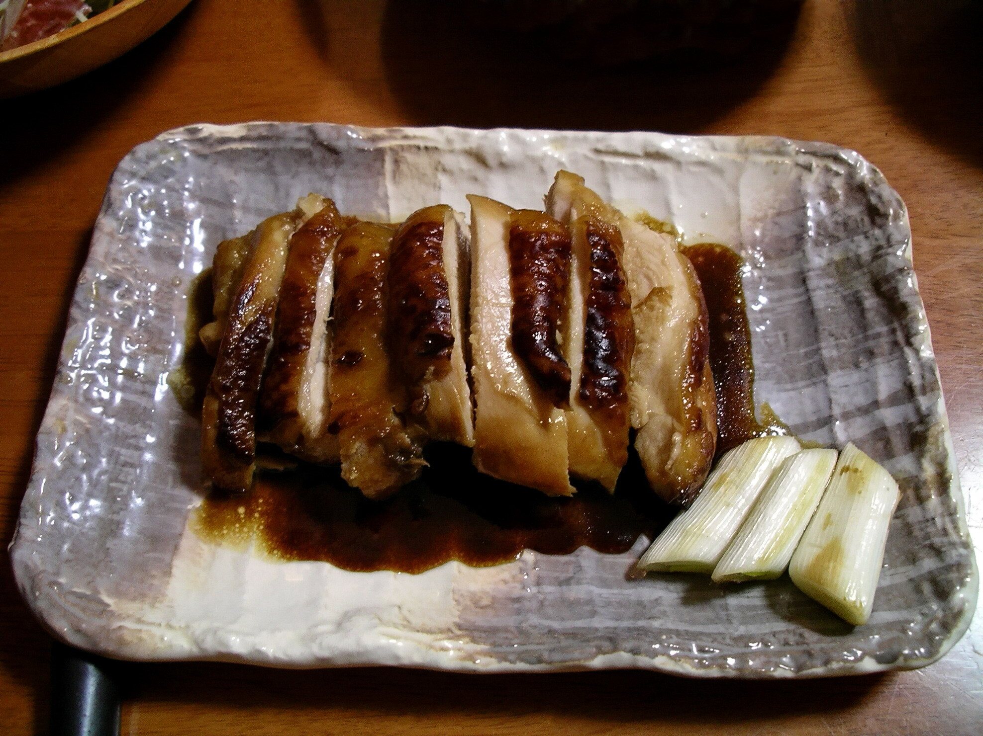 Sliced teriyaki chicken glazed with sauce on a rectangular plate